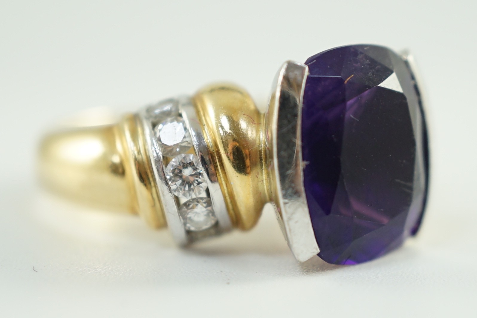 A modern 18ct gold and cushion cut amethyst set dress ring, with ten stone round cut diamond set shoulders